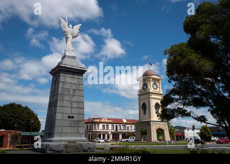 War Memorial und Uhrenturm, Manchester Square, Feilding, Manawatu, North Island, Neuseeland. Das Feilding Hotel in der Ferne. Stockfoto