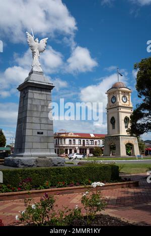 War Memorial und Uhrenturm, Manchester Square, Feilding, Manawatu, North Island, Neuseeland. Das Feilding Hotel in der Ferne. Stockfoto