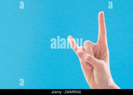 Weibchen, weiße Hand auf blauem Hintergrund, mit einer Ziegengeste, Stein, Nahaufnahme. Stockfoto