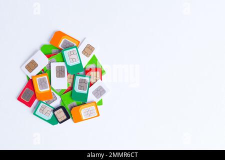 Heap verschiedener verwendeter SIM-Karten für die Mobilfunkkommunikation auf weißem Hintergrund, Kopierbereich. Stockfoto