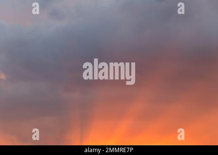 Der Himmel bei Sonnenuntergang mit Lichtstrahlen, die durch die Wolken strömen, ein sanfter, traumhafter Himmelsersatz. Stockfoto