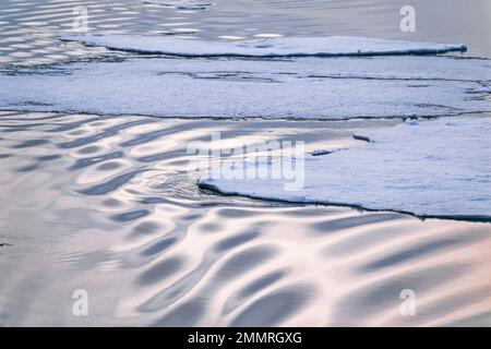 Eisschollen mit Wellenmustern im Wasser Stockfoto