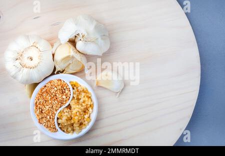 Zerstoßener Knoblauch auf hellem Holzhintergrund, mit selektiver Nahaufnahme. Stockfoto