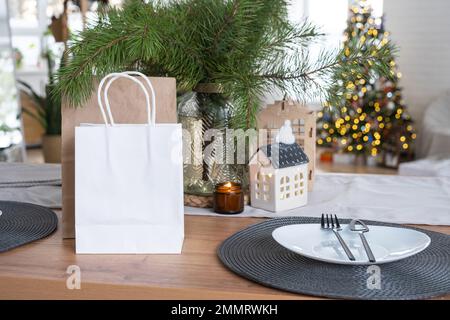 Papierpakete sind auf einem Küchentisch, der zu Weihnachten dekoriert ist. Einkäufe und Geschenke, Geschenke und Fertiggerichte werden geliefert und vorbereitet Stockfoto