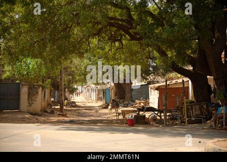 Straßenszene in Gambia, Westafrika. Ein subtropisches, warmes und sonniges Winterziel für Nordeuropäer. Die Einheimischen entspannen sich. Stockfoto