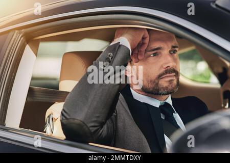 Im Morgenstau wird man genervt. Ein gutaussehender Geschäftsmann, der auf dem Weg zur Arbeit genervt aussah. Stockfoto