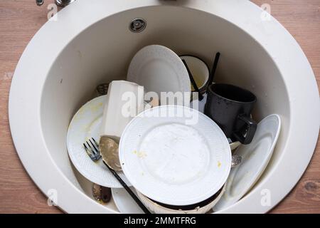 Dreckiges Geschirr im Waschbecken in der Küche, Chaos nach dem Mittagessen, zu faul, um Geschirr abzuspülen. Küchenreinigung, Waschmittel, Reinigungsservice Stockfoto