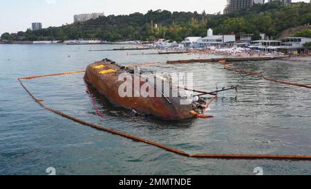 Die Leute ruhen sich am Strand in der Nähe des versunkenen Tankers aus. Ökologische Katastrophe am Ufer des Schwarzen Meeres. Stockfoto