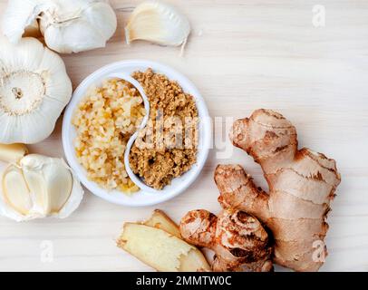 Zerstoßener Knoblauch auf hellem Holzhintergrund, mit selektiver Nahaufnahme. Stockfoto