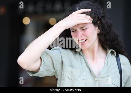 Frau beschwert sich über Migräne auf der Straße Stockfoto