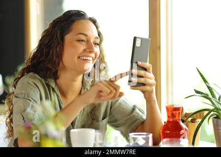 Glückliche Frau, die in einem Restaurant am Telefon lächelt Stockfoto