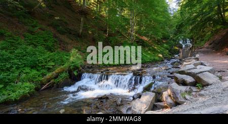 Wasserstrom im Wald. Landschaft mit kleinen Kaskaden und moosem Felsen. Sonniger Morgen im Sommer Stockfoto