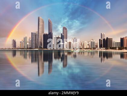 Regenbogen über der Skyline von Abu Dhabi mit Reflexionen im Meer, Vereinigte Arabische Emirate - Panorama Stockfoto