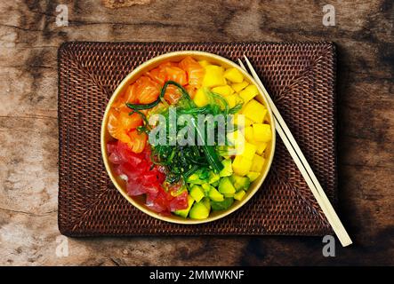 Japanisches Poki mit Sashimi-Lachs, Avocado, Udon, Wakame-Seetang, Thunfisch auf dem alten rostigen Holztisch. Stockfoto