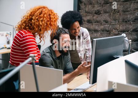 Lächelnde Gruppe von verschiedenen Geschäftsleuten, die gemeinsam über den Papierkram gehen und im Büro des Unternehmens arbeiten Stockfoto