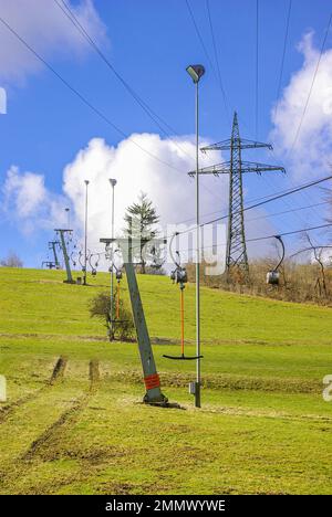 Skilift im Stillstand aufgrund von Schneemangel infolge des Klimawandels am Ende des Winters auf einem Hügel in Münsingen, Schwäbische Alb, Deutschland. Stockfoto