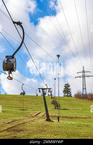 Skilift im Stillstand aufgrund von Schneemangel infolge des Klimawandels am Ende des Winters auf einem Hügel in Münsingen, Schwäbische Alb, Deutschland. Stockfoto