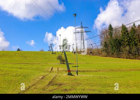 Skilift im Stillstand aufgrund von Schneemangel infolge des Klimawandels am Ende des Winters auf einem Hügel in Münsingen, Schwäbische Alb, Deutschland. Stockfoto