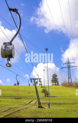 Skilift im Stillstand aufgrund von Schneemangel infolge des Klimawandels am Ende des Winters auf einem Hügel in Münsingen, Schwäbische Alb, Deutschland. Stockfoto