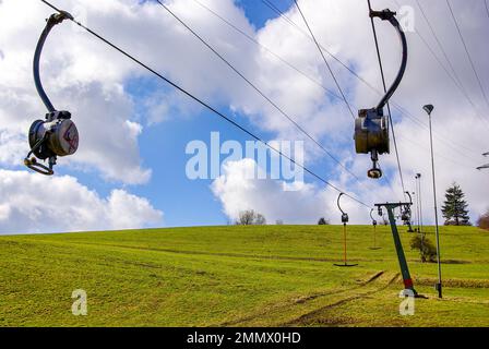 Skilift im Stillstand aufgrund von Schneemangel infolge des Klimawandels am Ende des Winters auf einem Hügel in Münsingen, Schwäbische Alb, Deutschland. Stockfoto