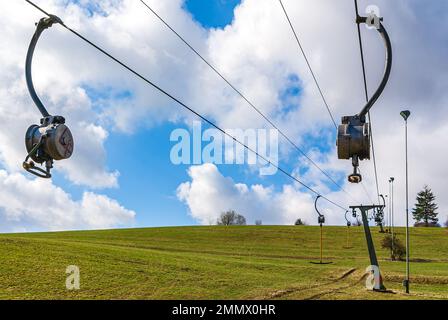 Skilift im Stillstand aufgrund von Schneemangel infolge des Klimawandels am Ende des Winters auf einem Hügel in Münsingen, Schwäbische Alb, Deutschland. Stockfoto