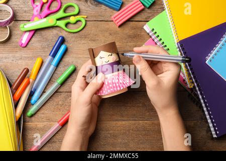 Eine Frau, die eine Spielzeugpuppe aus dem Toilettenpapier am Holztisch herstellt, Draufsicht Stockfoto