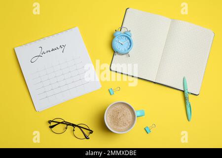 Flache Laienzusammensetzung mit Kalender und Tasse Kaffee auf gelbem Hintergrund Stockfoto