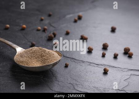 Gemahlener schwarzer Pfeffer und Mais auf schwarzem Tisch, Nahaufnahme Stockfoto