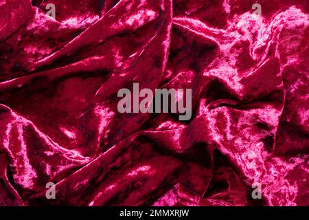 Roter Velor als Nahaufnahme des Hintergrunds verknittert, roter Samtstoff Stockfoto