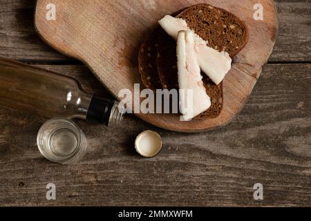 Ein Stück Brot mit Speck ein Glas Wodka auf dem Tisch, alkoholische Getränke und ein Snack, schlechte Gewohnheiten, Alkoholabhängigkeit, Essen und Getränke Stockfoto