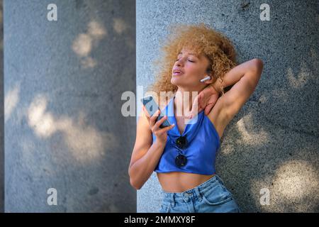 Junge brasilianische Frau mit Kopfhörern, die Musik hört und singt. Stockfoto