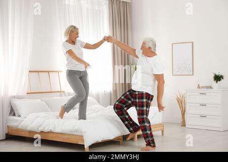 Glückliches, reifes Paar, das im Schlafzimmer tanzt Stockfoto