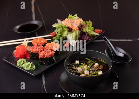 Japanische Küche. Lachs Sushi Nigiri und Miso Suppe auf schwarzem Teller, dunkler Tisch. Stockfoto