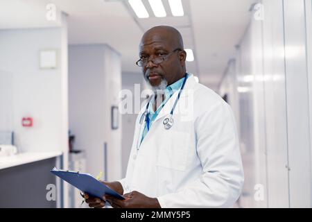 Porträt eines afroamerikanischen männlichen Arztes, der im Krankenhaus arbeitet, mit Klemmbrett Stockfoto
