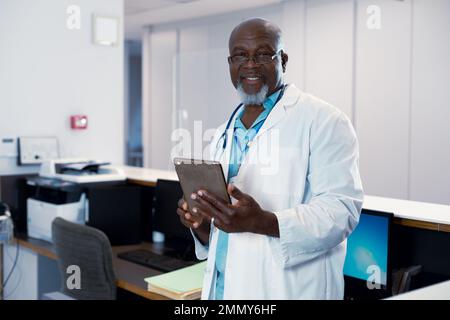 Portrait eines glücklichen afroamerikanischen männlichen Arztes, der im Krankenhaus arbeitet, hält Tablette Stockfoto