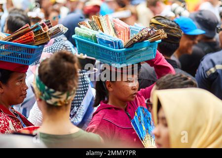 Ein Straßenverkäufer trägt seine Ware auf dem Kopf. Eine Art, Gewichte auf dem Kopf zu tragen. Bali, Indonesien - 03.02.2018 Stockfoto