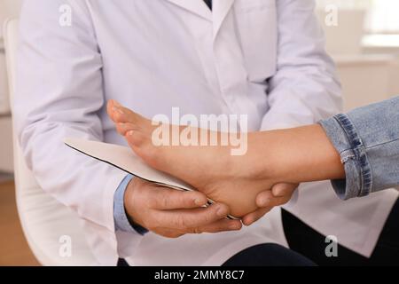 Die Einlegesohle des männlichen Orthopäden am Fuss des Patienten in der Klinik, Nahaufnahme Stockfoto