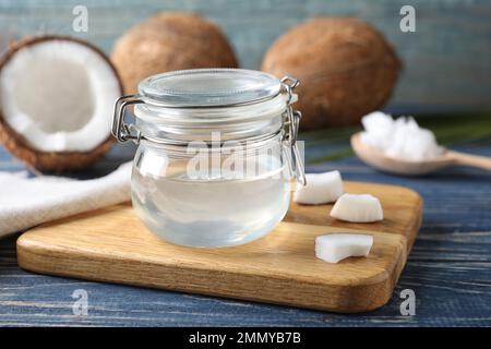 Kokosöl im Glas auf blauem Holztisch Stockfoto