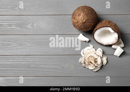 Flache Liegezusammensetzung mit leckeren Kokosnussplittern auf grauem Holztisch. Platz für Text Stockfoto