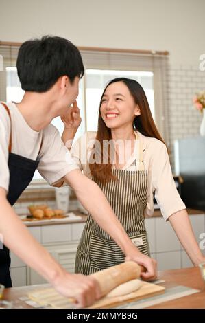 Ein junges asiatisches Paar, das beim Kochen von Speisen in der Küche spielt, romantische Momente in der Küche verbringt, genießt das Wochenende zu Hause. Ich Stockfoto