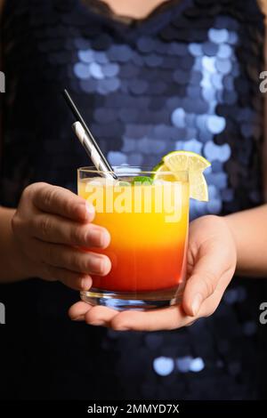 Frau mit einem Glas Tequila Sunrise, Nahaufnahme. Köstlicher alkoholischer Cocktail Stockfoto