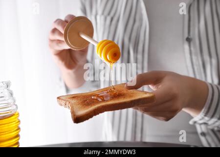 Eine Frau, die Honig auf getoastetes Brot schüttet Stockfoto