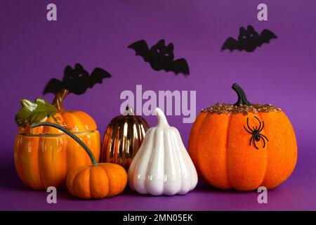 Halloween-Hintergründe mit weißen, orangefarbenen und goldenen Kürbissen, Spinnen und schwarzen Fledermäusen auf lila Hintergrund mit Spinnweben und schrecklicher Landschaft. Horror und Stockfoto