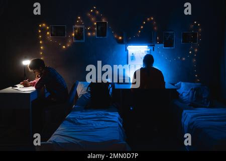 Ernsthafte Studenten, die nachts im Studentenwohnheim studieren. Stockfoto