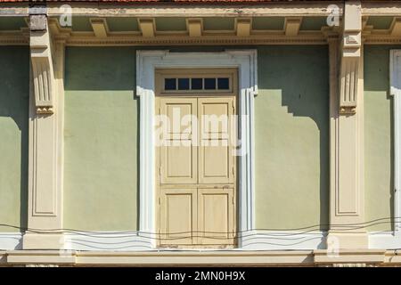 Eine wunderschöne altmodische Holztür eines historischen Ladenhauses mit hellgrünen Wänden in der Stadt Georgetown in Penang, Malaysia. Stockfoto