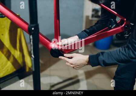 Mechaniker, der mit einem Schraubenschlüssel ein Sonderfahrrad in der Werkstatt zusammenbaut Stockfoto