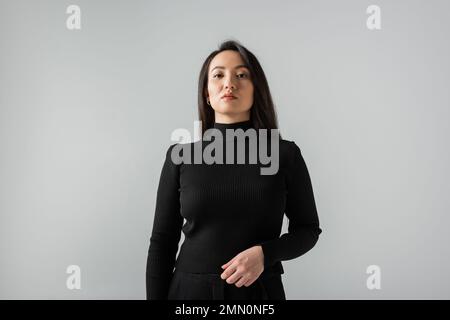 asiatische Geschäftsfrau in schwarzem Rollkragenpulli, die auf grau isoliert auf die Kamera schaut Stockfoto