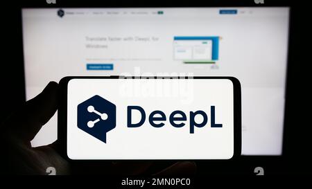 Person, die ein Smartphone mit dem Logo des neuronalen maschinellen Übersetzers DeepL auf dem Bildschirm vor der Website hält. Konzentrieren Sie sich auf das Display des Telefons. Stockfoto