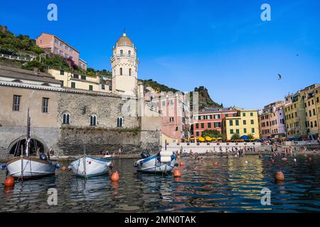 Italien, Ligurien, Nationalpark Cinque Terre, UNESCO-Weltkulturerbe, Dorf Vernazza, Pfarrkirche Saint Margaret of Antioch (Santa Margherita), flankiert von einem hohen achteckigen Glockenturm und der Strand im Hafen auf der rechten Seite Stockfoto