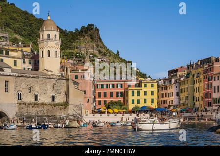 Italien, Ligurien, Nationalpark Cinque Terre, UNESCO-Weltkulturerbe, Dorf Vernazza, Pfarrkirche Saint Margaret of Antioch (Santa Margherita), flankiert von einem hohen achteckigen Glockenturm und der Strand im Hafen auf der rechten Seite Stockfoto